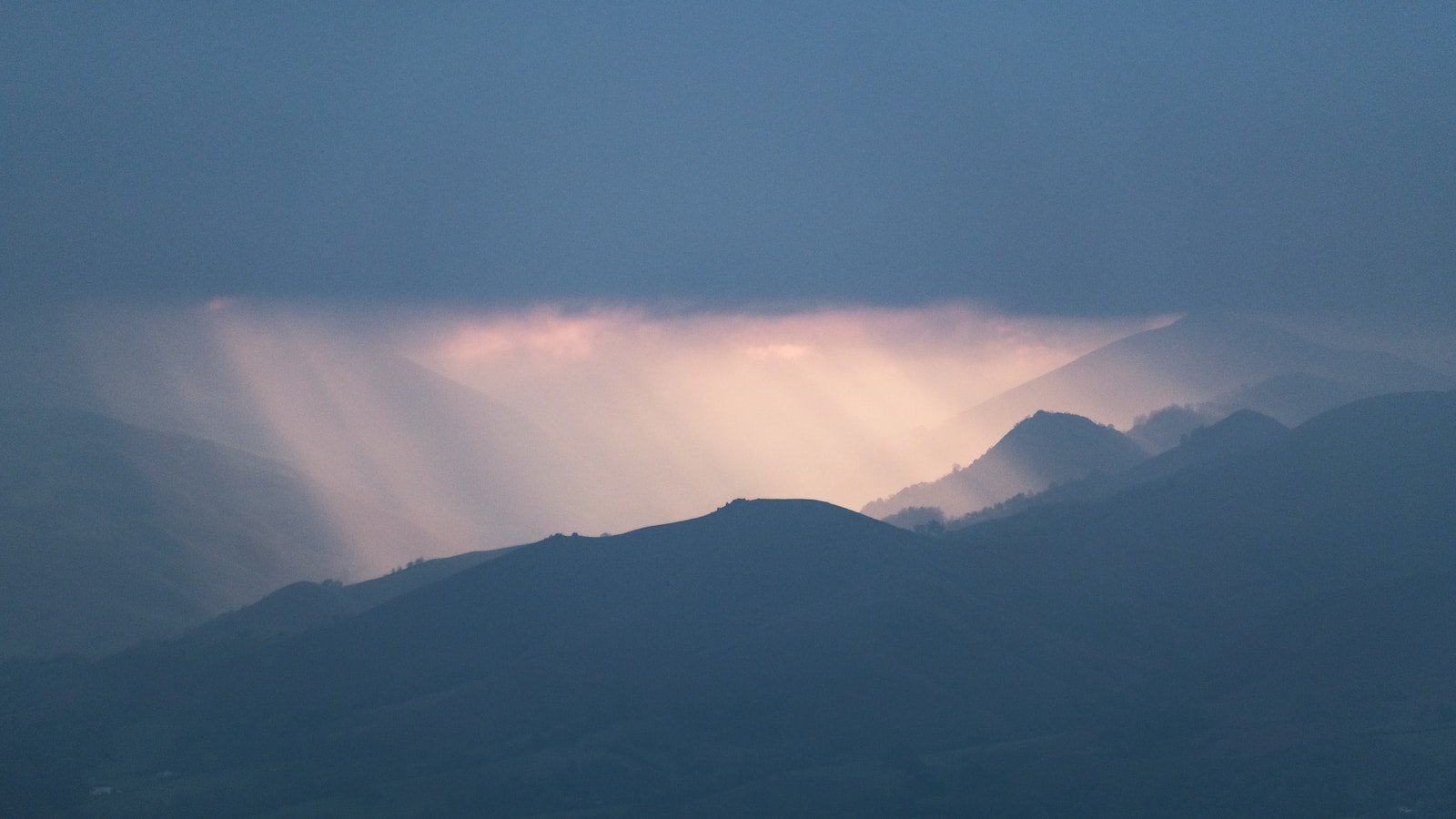 the sun shines through the clouds over the mountains